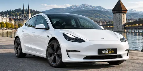 Weisser Tesla Model 3 von Taxi To Go 24 am Luzerner Quai, im Hintergrund der Wasserturm